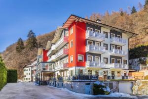 un bâtiment rouge avec des balcons blancs sur une montagne dans l'établissement Hotel Vittoria - Ricarica l'anima, à Dimaro