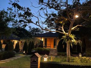 una casa con una pajarera en el patio por la noche en Khaokhab Lodge, en Nong Nam Daeng