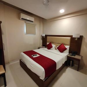 a bedroom with a large bed with red pillows at Oxford Hotel Powai in Mumbai