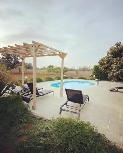 un patio con sedie e un pergolato accanto alla piscina di La Casa di Flò Luxury Rooms ad Alezio