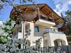une maison entourée d'une terrasse couverte et d'un toit en bois. dans l'établissement Les Gomines BB*****, à San Vigilio Di Marebbe