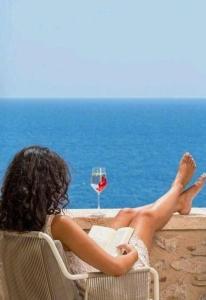 a woman sitting in a chair reading a book and a glass of wine at Orbi City Batumi With Sea View in Batumi