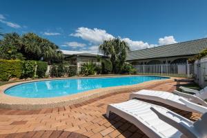 a patio area with a pool and a lawn chair at Sunshine Coast Airport Motel in Marcoola
