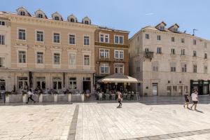 a group of people riding skateboards in a plaza in front of buildings at Main Square Duplex with Rooftop Terrace in Split