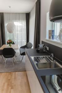 eine Küche mit einem Waschbecken und einem Tisch mit Stühlen in der Unterkunft Haus Karlsbad - neu und modern in Velden am Wörthersee