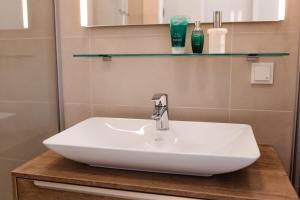 een badkamer met een witte wastafel en een spiegel bij Haus Karlsbad - neu und modern in Velden am Wörthersee