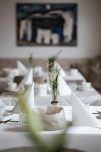 une table avec des assiettes blanches et un vase de fleurs dans l'établissement Garni Hotel Platzer, à Burgusio