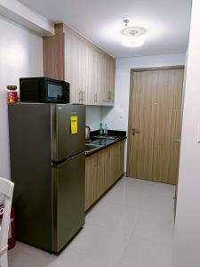 a kitchen with a stainless steel refrigerator and wooden cabinets at Home away from Home in Manila