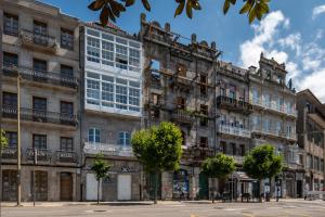 ein altes Gebäude in einer Stadt mit Bäumen davor in der Unterkunft Bow Homes by Como en Casa in Vigo