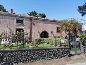 a house with a fence and a stone wall at Palmento Spuligni in Zafferana Etnea
