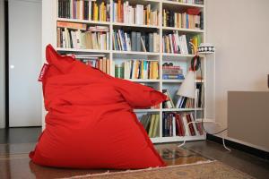 a large red pillow sitting in front of a book shelf at B&B BnBeach in Varazze
