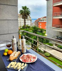 - une table avec de la nourriture et des verres de vin sur le balcon dans l'établissement Apartamento turístico en Sanxenxo, à Sanxenxo