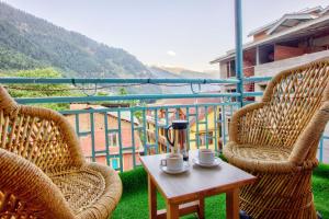 a balcony with two chairs and a table with cups on it at HOTEL ROYAL Manali in Manāli