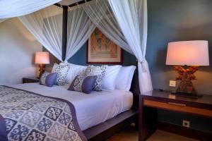 a bedroom with a bed with a canopy and two lamps at Villa Nirwana in Tanah Lot