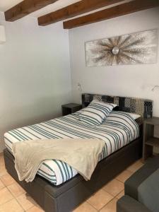Schlafzimmer mit einem Bett mit gestreifter Decke in der Unterkunft Le petit monas in Civaux