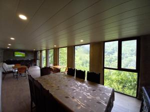 a dining room with a table and chairs and windows at Hotel Villa Borjomi in Borjomi