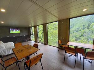a living room with tables and chairs and windows at Hotel Villa Borjomi in Borjomi