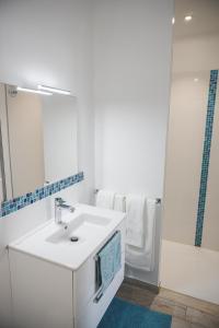 La salle de bains blanche est pourvue d'un lavabo et d'un miroir. dans l'établissement Le Clos des Fantaisies, à Rivedoux-Plage