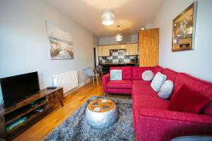 a living room with a red couch and a flat screen tv at Royal Harbour Retreat - Balcony, sea view property in Ramsgate