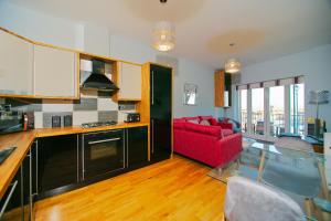 a kitchen and living room with a red couch at Royal Harbour Retreat - Balcony, sea view property in Ramsgate