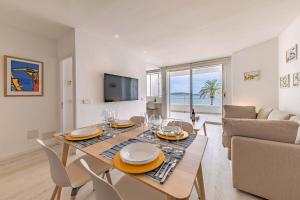 uma sala de jantar e sala de estar com mesa e cadeiras em Beachfront Apartment Sivella Mar em Port de Pollença