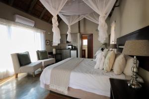 a bedroom with a large white bed with curtains at Tshukudu Game Lodge in Hoedspruit