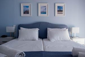 Schlafzimmer mit einem Bett mit weißer Bettwäsche und Kissen in der Unterkunft Mirtia Hotel in Pefki