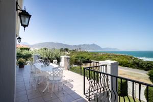 a balcony with a table and chairs and the ocean at On The Rocks in Hermanus