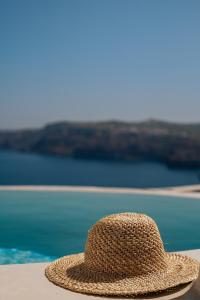 a straw hat sitting on a table near the water at Akrorama private villas and suites in Akrotiri