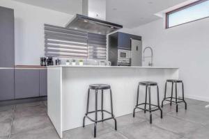 a kitchen with three bar stools at a counter at Villa Ponzos Chalet independiente y privado in Triquivijate