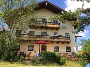 ein großes Haus mit einem Balkon mit Stühlen und einem Sonnenschirm in der Unterkunft Ferienhaus am Waginger See in Kirchanschöring