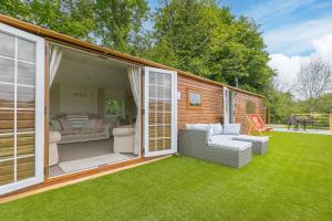 a screened in porch with a couch and chairs on the grass at Lazy Lodge in Redruth