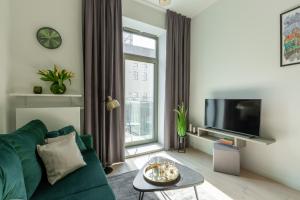 a living room with a green couch and a tv at Apartament Księżycowy - Młyn Maria - Art Apartments in Wrocław