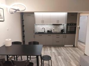 a kitchen with white cabinets and a black table and chairs at Uroczy apartament w ścisłym centrum Giżycka in Giżycko