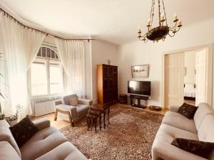 a living room with two couches and a tv at The Best Location salon apartment with main street view in Sarajevo