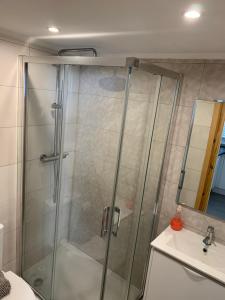 a shower with a glass door next to a sink at CASA DAS MOURAS in Faro