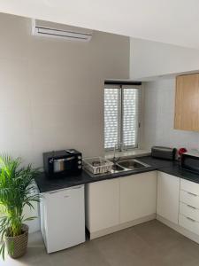 a white kitchen with a sink and a microwave at CASA DAS MOURAS in Faro