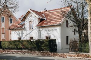 une maison blanche avec un toit rouge dans l'établissement Villa100und10 by Seebnb, à Klagenfurt am Wörthersee