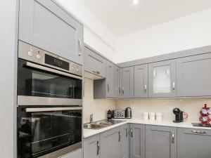 una cocina con electrodomésticos de acero inoxidable y armarios grises en Flat 3 en Saltburn-by-the-Sea
