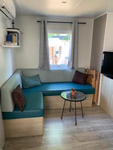uma sala de estar com um sofá azul e uma mesa em Le mobilhome de Evelyne et Serge em Lit-et-Mixe