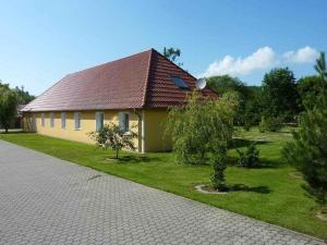 ein gelbes Haus mit rotem Dach auf einem Hof in der Unterkunft Haus der Seeadler - Appartementhaus Haus der Seeadler - Fewo 4 in Borchtitz