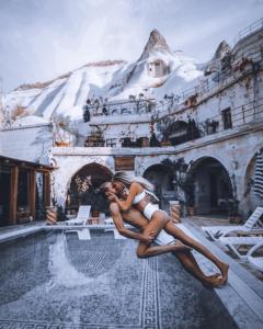 a woman is sitting on the edge of a swimming pool at Local Cave House Hotel in Göreme