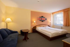 ein Hotelzimmer mit einem Bett und einem Sofa in der Unterkunft Hotel Mohelnice in Mohelnice