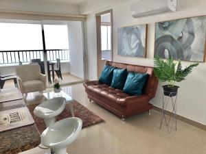 sala de estar con sofá de cuero marrón y almohadas azules en apartamento en bocagrande, en Cartagena de Indias