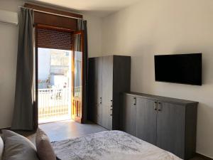 1 dormitorio con 1 cama y TV en la pared en Casa-Riposto, en Riposto