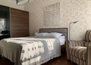 ein Schlafzimmer mit einem großen Bett und einem Stuhl in der Unterkunft Sunset Residence - 5 min to the beach! in Narva-Jõesuu