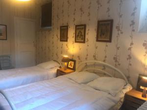 two beds in a bedroom with two lamps and wallpaper at Luchon centre - maison de ville calme et lumineuse in Luchon