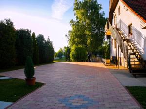 a brick driveway next to a building with a staircase at Tenisz Vendégház in Ordacsehi