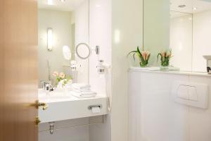 a white bathroom with a sink and a mirror at Hotel & Spa Der Steirerhof in Bad Waltersdorf