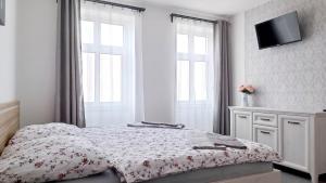 1 dormitorio blanco con 1 cama y TV en la pared en Penzion HARMONIE en Trhové Sviny